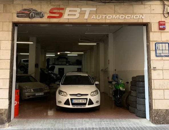 Fachada del taller SBT Automoción en la Calle Emilio Rico, 12 de Elda, con un coche en la entrada